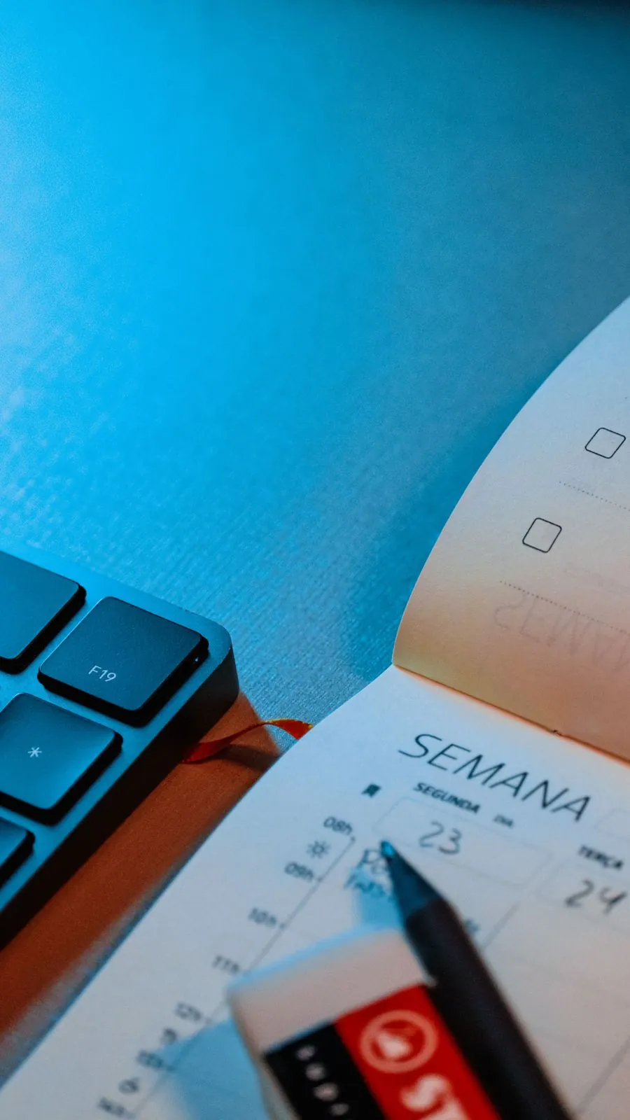Agenda semanal aberta ao lado do teclado, marcando prazos do dia